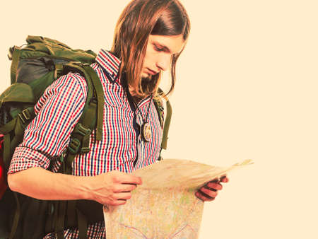 Man tourist backpacker reading map on trip. Young guy hiker searching looking for direction guide. Male backpacking. Summer vacation travel.  の写真素材