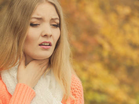 Sick woman in fall autumn park. Ill girl caught cold flu outdoor. Rhinitis or allergy. Health care.