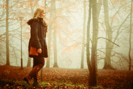 Solitude concept. Sad lonely woman walking relaxing in foggy day in romantic autumn forest park outdoorの写真素材