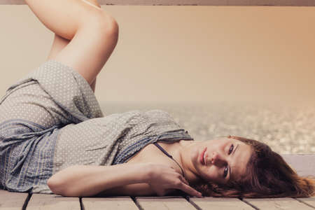 Holidays summer relaxation concept. Young woman relaxing on pier outdoorの写真素材
