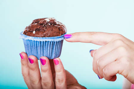 Delicious tasty sweet chocolate muffin in human hands. Confectionery food. Gluttony concept.の写真素材