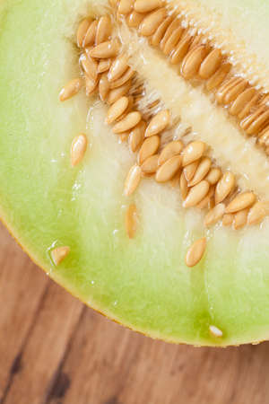 Closeup of melon with pips on wooden table. Fruit, diet and healthy nutrition.の写真素材
