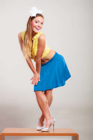 Alluring seductive pretty pin up girl wearing hairband bow, skirt and high heels. Attractive gorgeous young retro woman dancing on table.の写真素材