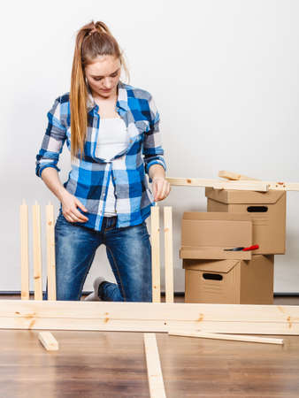 Woman moving in assembling furniture at new home. Young girl arranging apartment house interior and unpacking boxes. DIY.の写真素材