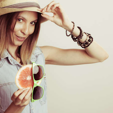 Happy glad fashionable woman tourist in straw hat holding sunglasses and grapefruit. Summer fashion.の写真素材