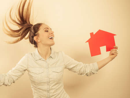 Happy young woman girl holding red paper house and key dreaming about new home house. Housing and real estate concept. の写真素材