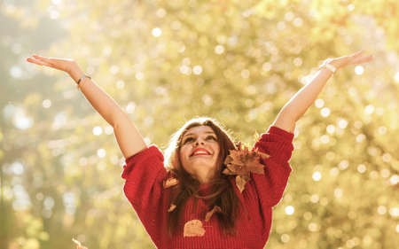 Happiness carefree. woman relaxing in autumn park throwing leaves up in the air with arms raised up. Beautiful girl in colorful forest foliage outdoor.の写真素材