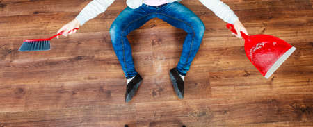 Cleanup housework concept. cleaning woman sweeping wooden floor with red small whisk broom and dustpan unusual high angle viewの写真素材