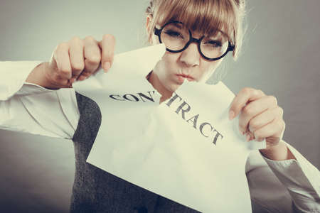 Business, documents and legal concept - serious unhappy businesswoman tearing crumpled contractの写真素材