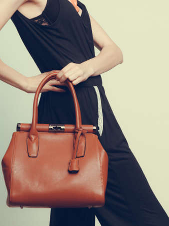 Elegant fashionable woman with leather handbag. Stylish girl holding brown bag. Female fashion vogue. Studio.の写真素材