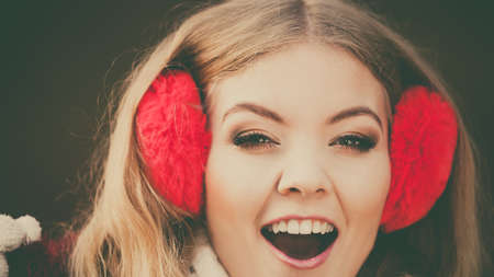 Portrait of pretty smiling fashionable woman in fall forest park. Happy gorgeous young girl in red earmuffs. Autumn winter fashion.の写真素材