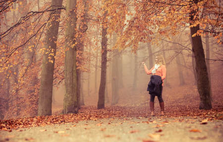 Lost confused woman in foggy fall autumn park searching direction. Fashion young girl holding jacket. Female looking for guidance in forest.の写真素材