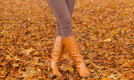 Closeup of woman legs in brown boots. Girl in autumn park forest. Fall winter fashion.の写真素材