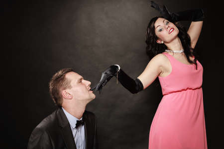 Date. Gallant man in suit and woman in evening dress on black grey background in studio.の写真素材