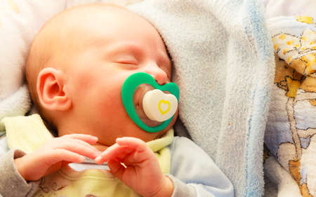 Closeup little newborn baby girl 24 days sleeping with dummy in mouth