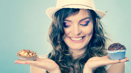 bakery, sweet food and people concept. closeup smiling summer woman curly hair straw hat holding cakes cupcakes in handsの写真素材