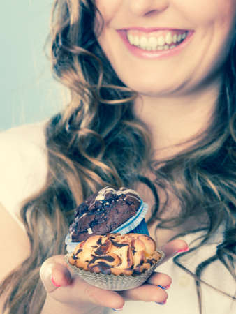 Bakery, sweet food and people concept. Closeup smiling summer woman curly hair holding cakes cupcakes in hands   の写真素材