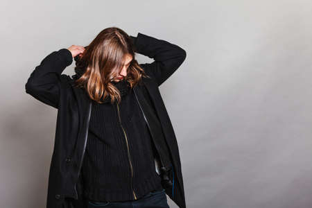 Portrait of handsome fashionable man wearing black coat and scarf. Young guy posing in studio. Winter or autumn fashion.の写真素材