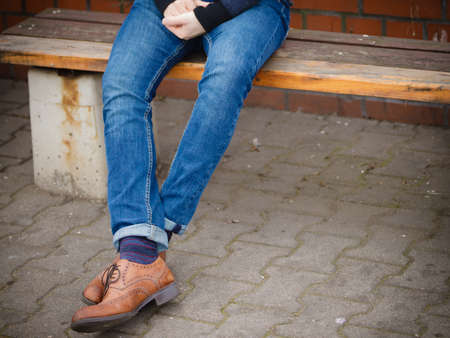 Autumn fashion, foot wear. Male legs in jeans and boots striped socks outdoor on streetの写真素材