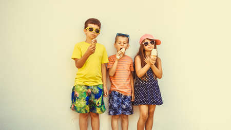 kids eating gelato and soft serve ice cream. boys and little girl in sunglasses enjoying summer holidays vacation.の写真素材