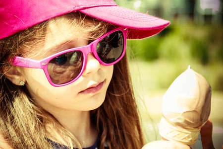 Kid eating gelato soft serve ice cream. Little girl in sunglasses enjoying summer holidays vacation...