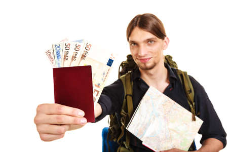 Man tourist backpacker holding map and passport full of money. Young guy hiker backpacking. Summer vacation travel. Studio shot. Isolated on white background.の写真素材