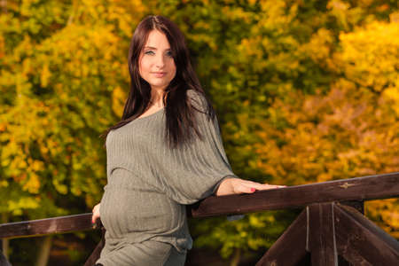 Pregnancy, motherhood and happiness concept. Relaxed calm pregnant woman walking outside in autumn parkの写真素材