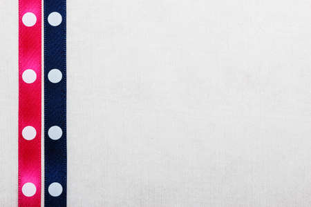 Festive celebration party frame. Polka dot navy blue and pink satin ribbon on white cloth backgroundの写真素材
