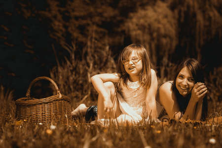 Mother parent and daughter child on picnic. Summer vacation leisure. Happy family relaxing in park meadow. Sepia.の写真素材