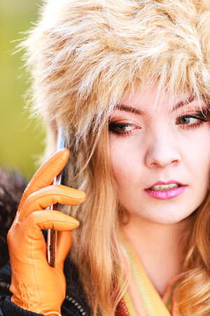 Portrait of pretty fashionable woman talking on mobile phone. Gorgeous young girl in fur winter hat...