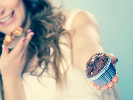 Bakery, sweet food and people concept. Closeup smiling summer woman curly hair holding cakes cupcakes in hands  の写真素材