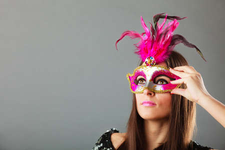 Holidays, people and celebration concept. Closeup woman face with carnival venetian mask on gray background.の写真素材