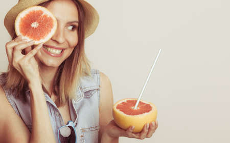 Woman having fun covering her eye with grapefruit. Happy summer vacation holiday. Healthy food.の写真素材