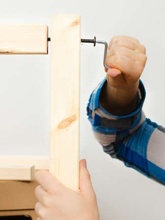 Human hand assembling wooden furniture using hex key. DIY enthusiast. Home improvement.の写真素材