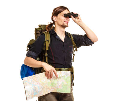 Man tourist backpacker holding map looking through binoculars. Young guy hiker backpacking. Summer vacation travel. Isolated on white background.の写真素材