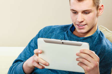 Modern technology leisure and relax concept. handsome man with pc computer tablet relaxing on couch