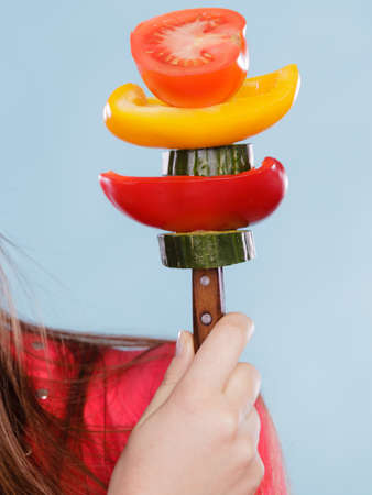 Closeup of human hands holding fork with fresh vegetables like tomato, pepper and cucumber. Dieting and slimming. Healthy nutrition.の写真素材