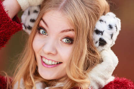 Portrait of pretty smiling fashionable woman in fall forest park. Happy gorgeous young girl in fur earmuffs. Autumn winter fashion.の写真素材