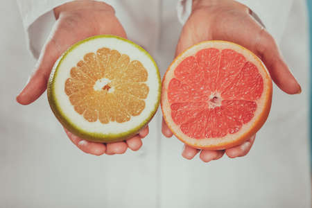 Person human holding grapefruits in hands promoting healthy food fruit. Right eating nutrition and slimming concept.の写真素材