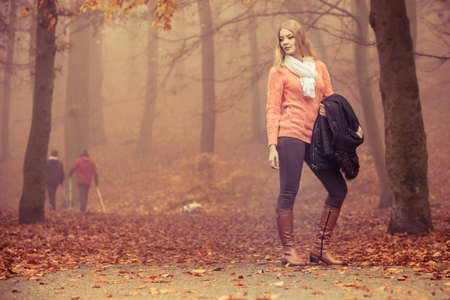 Fashion woman in foggy fall autumn park. Attractive full length young girl holding jacket. Happiness and relax in forest.の写真素材
