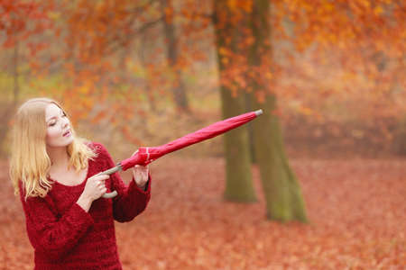 Smiling happy fashion cute woman girl in maroon sweater with umbrella relaxing in fall autumn park. Happiness and relax in forest.の写真素材