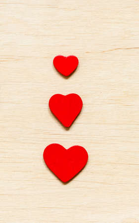 Valentine's day background. Red decorative three hearts on wooden background with copy spaceの写真素材