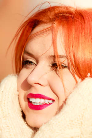 Winter fashion. Beauty face portrait red hair young woman in warm clothing outdoor enjoying sunlight...