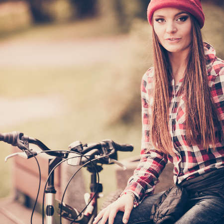 Fall active lifestyle concept,. Beauty young woman sporty casual girl relaxing in autumnal park with bicycle, outdoorの写真素材