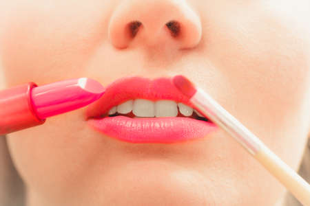 Close up of woman applying lipstick with brush on lips. Girl beautifying herself. Beauty and make up concept.の写真素材
