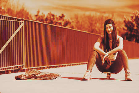 Summer sport and active lifestyle. Cool teenage girl skater riding skateboard on the street by...