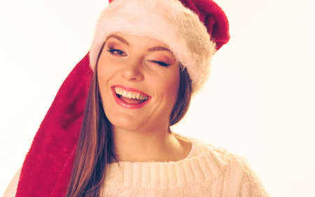 Christmas happiness concept. Portrait of smiling beautiful winking woman in santa hat.の写真素材