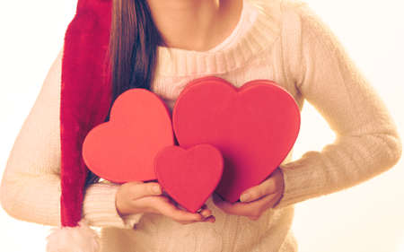 Christmas winter happiness concept. Woman wearing santa helper hat holding many red heart shaped...