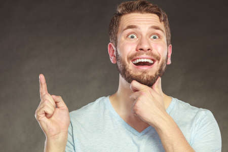Portrait of surprised scared handsome man pointing at empty blank copy space. Young guy in studio on...