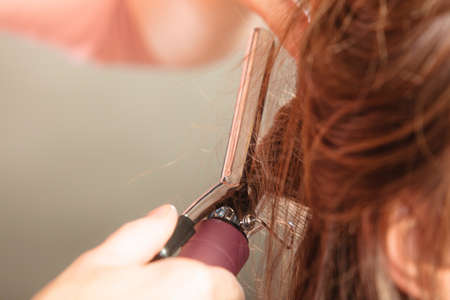 Stylist curling hair for pretty woman. Girl care about her hairstyle